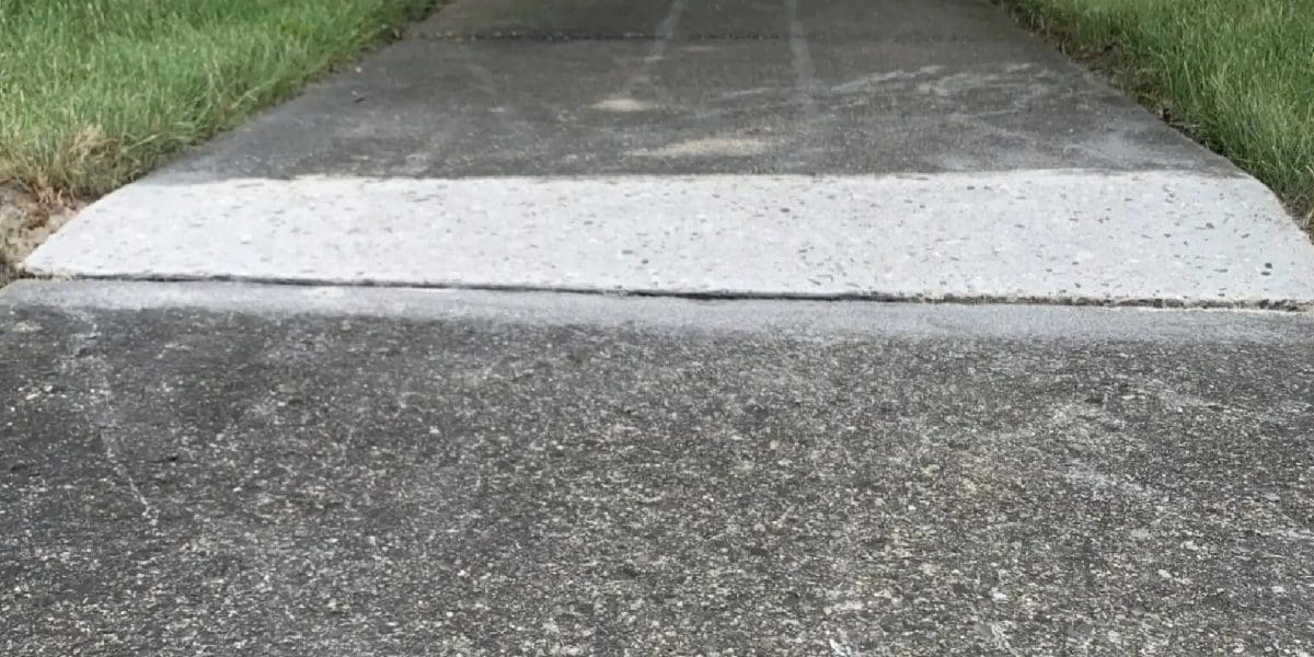 Concrete sidewalk with a marked uneven edge before repair
